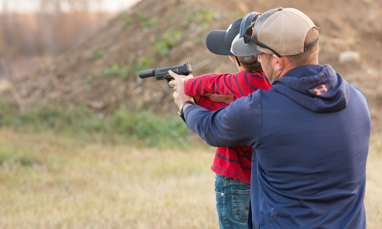 An instructor coaching a student, both wearing ear protection